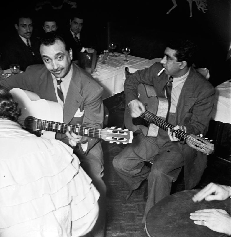 Django Reinhardt et son frère Joseph jouent au Jimmy's bar au milieu des tables en décembre 1947.