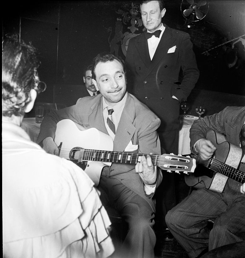 Django Reinhardt et son frère Joseph jouent au Jimmy's bar au milieu des tables en décembre 1947.