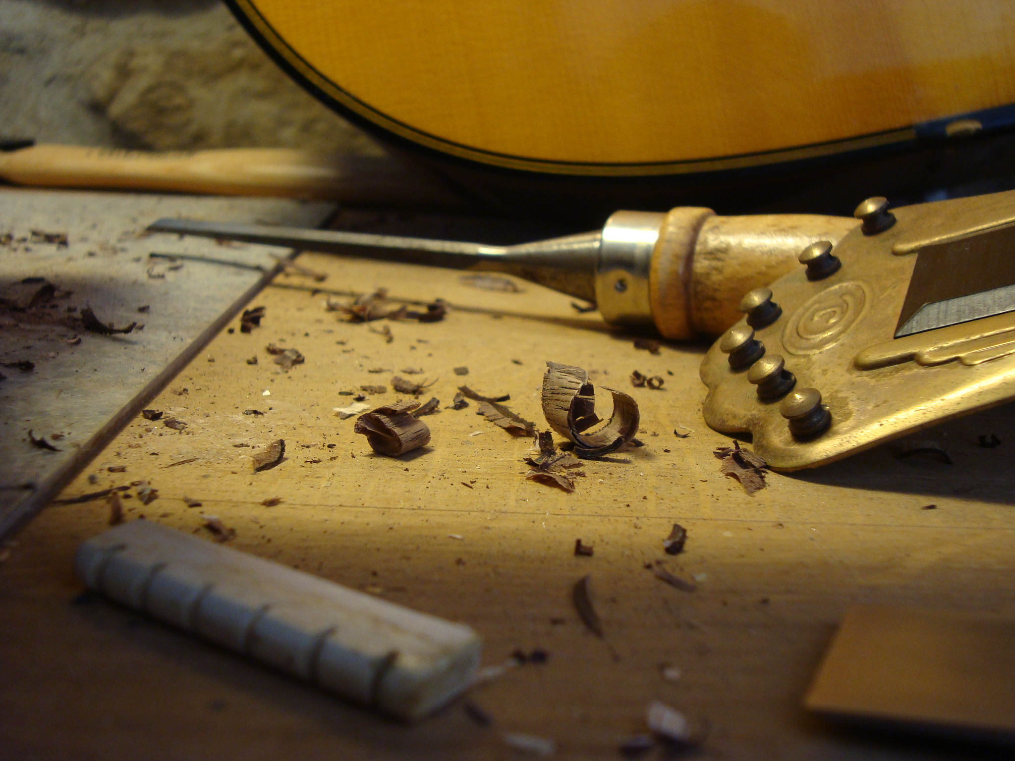 Photo d'un établi de luthier de guitare manouche ou gypsy guitar, zoom sur cordier, copeaux de bois, sillet en os
